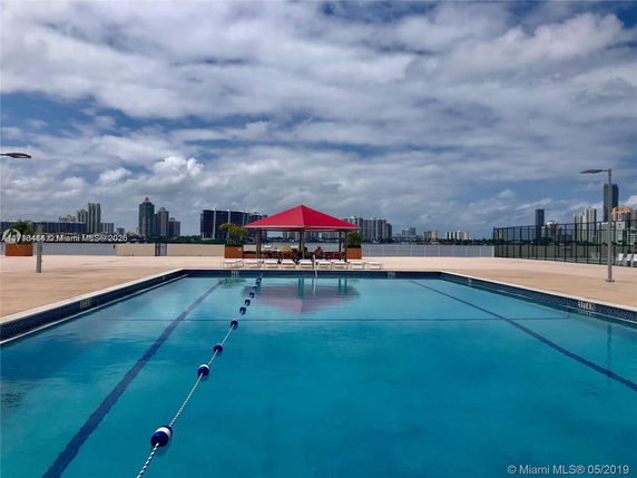View of a swimming pool on a rooftop with cityscape in the background.