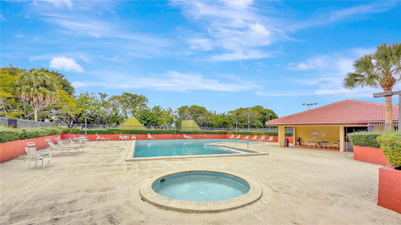 Outdoor swimming pool area with surrounding chairs and small pool.