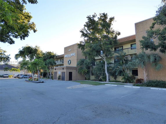 Front view of a multi-story building with balconies and a parking area.