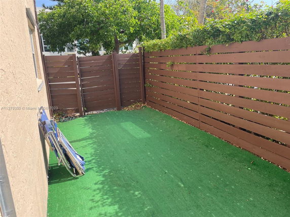 Outdoor area with artificial grass and wooden privacy fence.