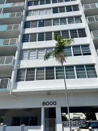 Front view of a multi-story building with balconies and a central entryway.