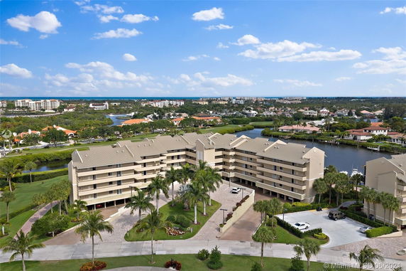 Aerial view of a multi-story residential complex with balconies and a canal in a suburban area.