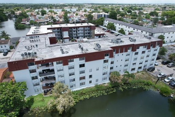 Aerial view of a multi-story apartment building by a water body.