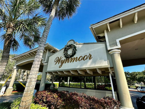 Front view of a building entrance with a 'Wynmoor' sign and decorative columns.