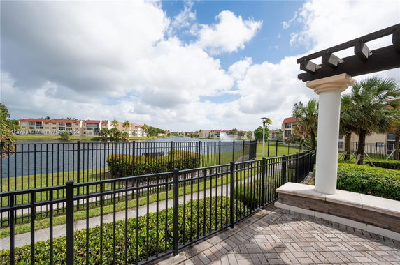 View of a lake and surrounding apartments with a patio and railing in the foreground.