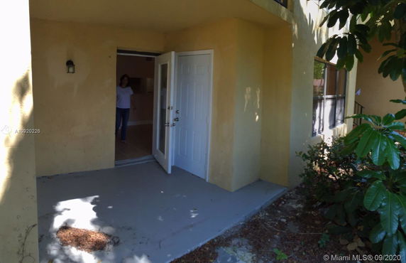 Front view of a house with open entry door and yellow walls.