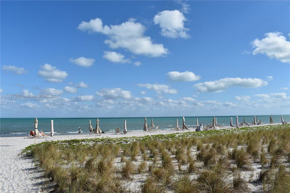 Beach view with sand, sea, and umbrellas.