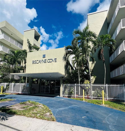 Front view of a multi-story building labeled Biscayne Cove with balconies and a covered entrance.