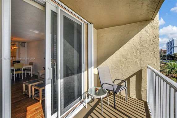 View from a balcony with a chair and small table, overlooking nearby buildings.