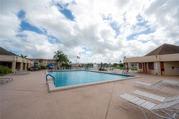 Outdoor swimming pool area with lounge chairs and umbrellas.