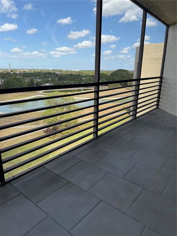 View from a balcony overlooking a grassy area and surrounding landscape.