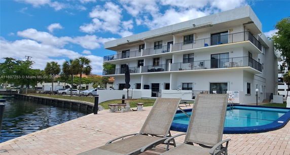 Three-story building with balconies next to a small swimming pool.