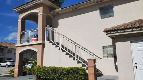 Side view of a two-story house with an external staircase and balcony.