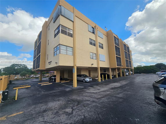 Front view of a multi-story apartment building with covered parking.