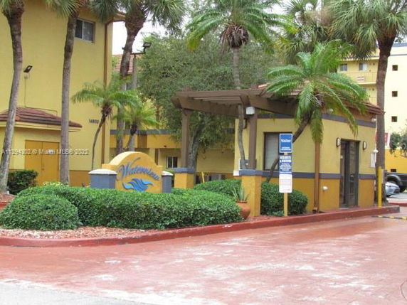 Entrance view of a building with a yellow exterior, palm trees, and a sign reading 'Waterway'.