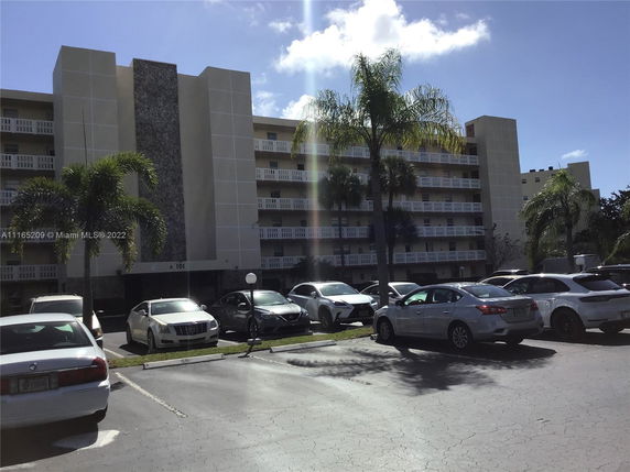 Front view of a multi-story residential building with a parking area in front.