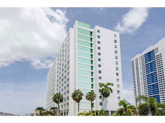 Front view of a multi-story building with a modern design and palm trees in the foreground.