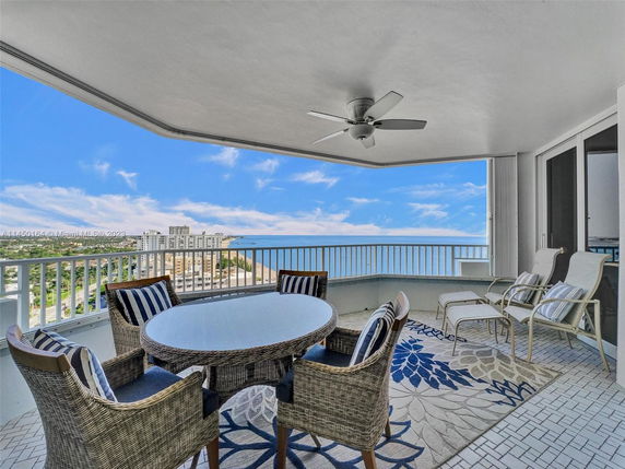 View from a balcony overlooking a coastal cityscape with buildings and ocean.