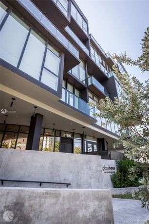 Front view of a modern multi-story building with large glass windows and balconies.