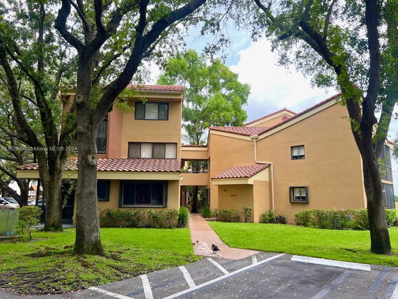 Front view of a multi-story residential building with a tiled roof and beige exterior.