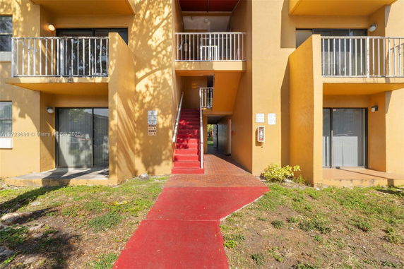 Front view of a multi-story building with small balconies and a central staircase.