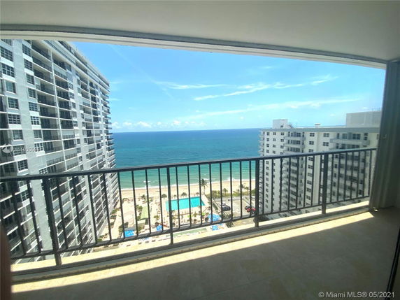 Panoramic view of the ocean and high-rise buildings from a balcony.