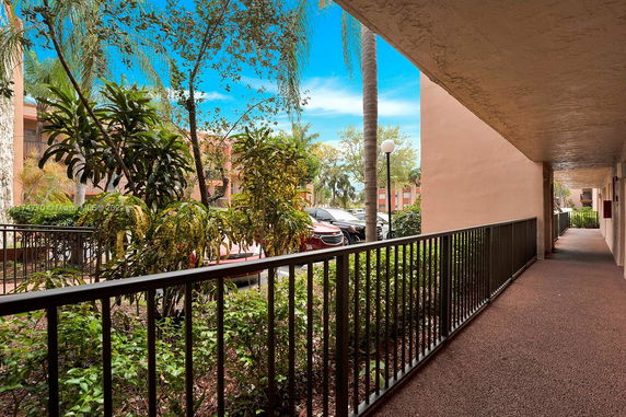 View of a corridor with plants and parking area visible outside.