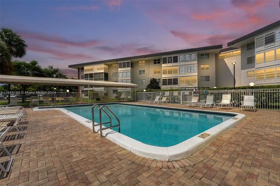Outdoor swimming pool area in front of a residential building.