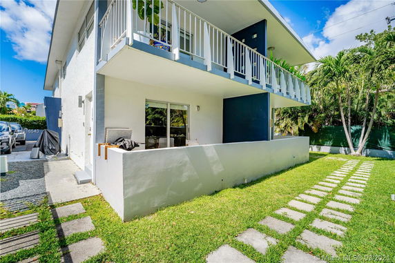 Front view of a two-story house with a balcony and patio area.