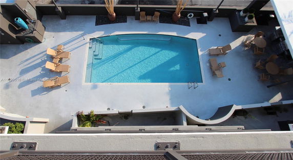 Aerial view of a swimming pool with lounge chairs and tables around it.