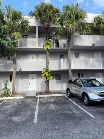 Front view of a multi-story building with a parking area in front.