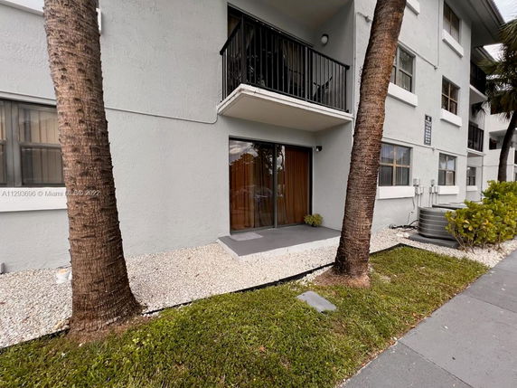 Front view of a multi-story building with balconies and sliding glass doors on the ground floor.