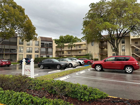 Front view of a multi-story residential building with parking area.