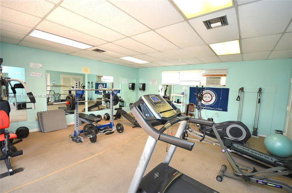 Room equipped with exercise machines and free weights in a gym setting.