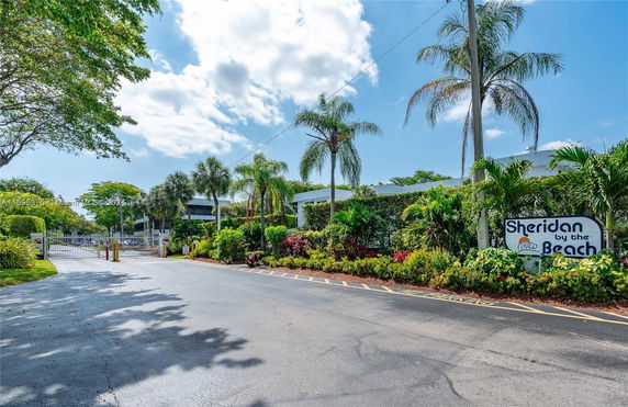 Front view of a building with a gated entrance and lush vegetation.