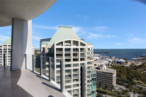 Panoramic view from a high-rise balcony overlooking nearby buildings and a marina.