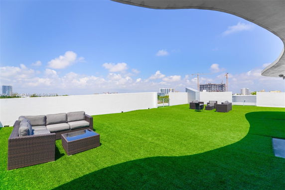 Rooftop area with artificial grass and outdoor seating.
