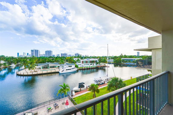 Wide-angle view from a balcony overlooking a river with boats and distant buildings.