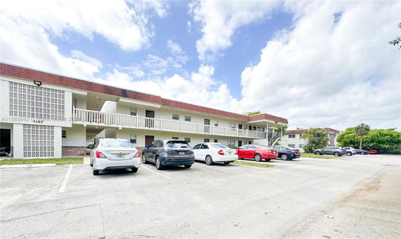 Front view of a two-story residential building with a parking area.