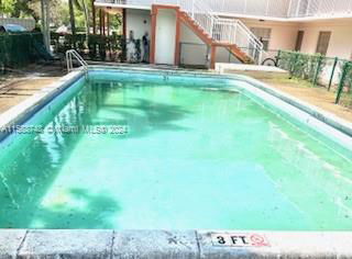 Outdoor swimming pool with a surrounding fence and adjacent building.