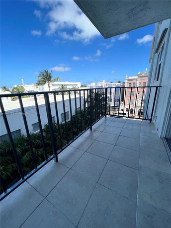 View from a balcony looking out over nearby buildings and palm trees.
