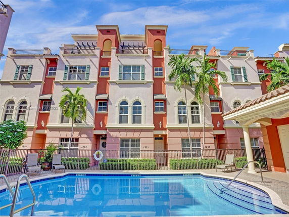 Front view of a multi-story apartment building with a swimming pool in the foreground.