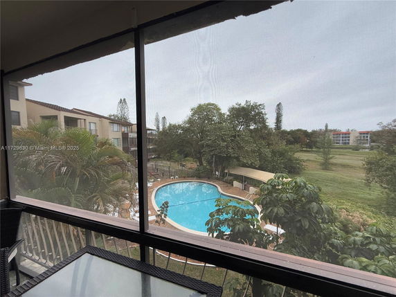 Panoramic view from a building overlooking a swimming pool and surrounding greenery.