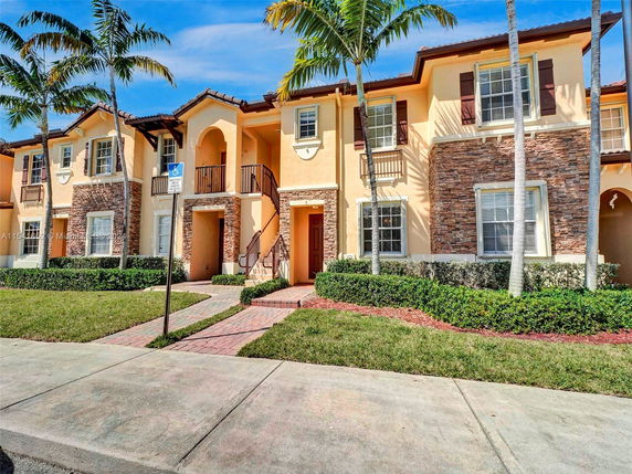 Front view of a two-story townhouse complex with stone and stucco exterior.