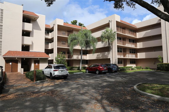 Front view of a multi-story residential building with balconies and parking area.