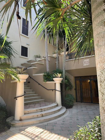 Staircase leading to the entrance of a building with palm trees surrounding.