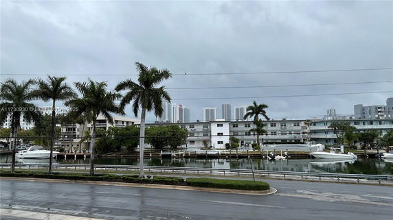 View of a waterfront area with boats and a multi-story building in the background.