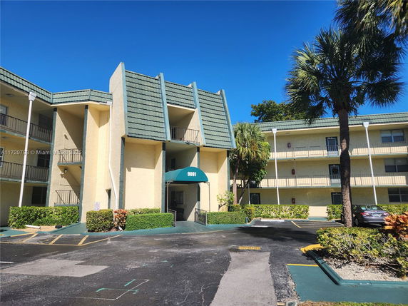 Front view of a multi-story building with green awning and balconies.