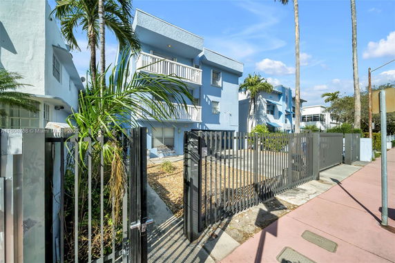 Front view of a two-story blue building with balconies and a gated entrance.