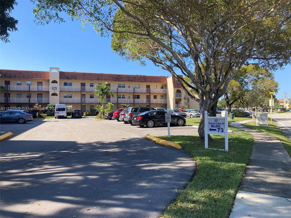 Front view of a three-story apartment building with a parking area in front.